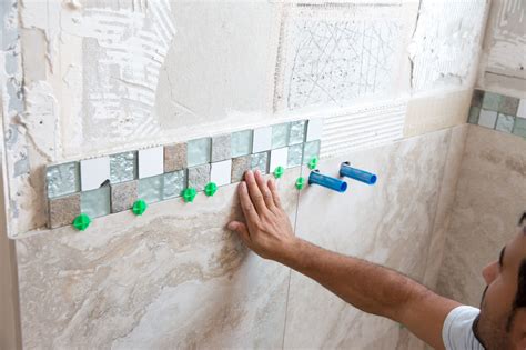 Screw a straight board to the level line and stack tile on the board. When you’ve completed tiling above the board and the tiles are held firmly, remove the board and cut the first row of tile to fit. Leave a 1/8-in. space between the tub and the tile to allow installation of a flexible bead of caulk.